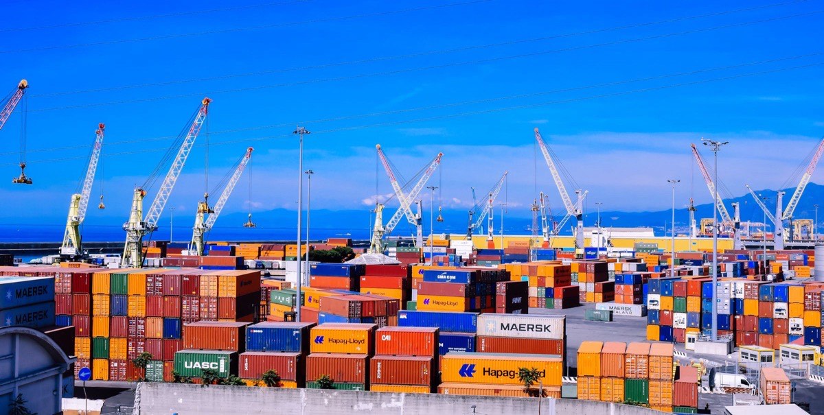 Stacked shipping containers and cranes at a busy container terminal