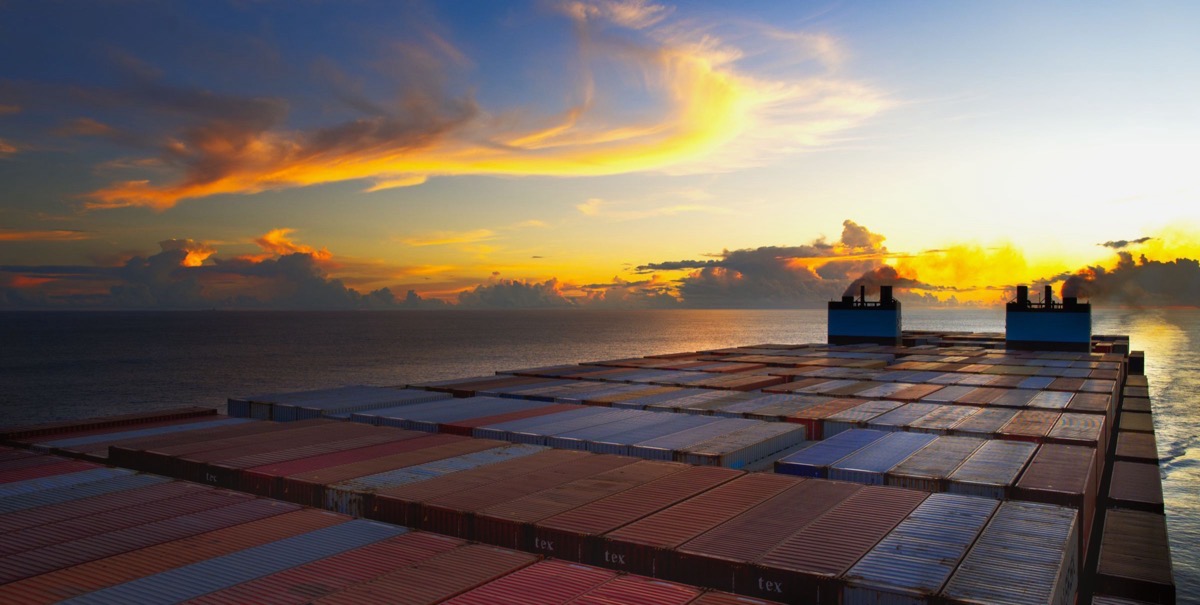 View across the container stacks of a cargo ship at sea at sunset
