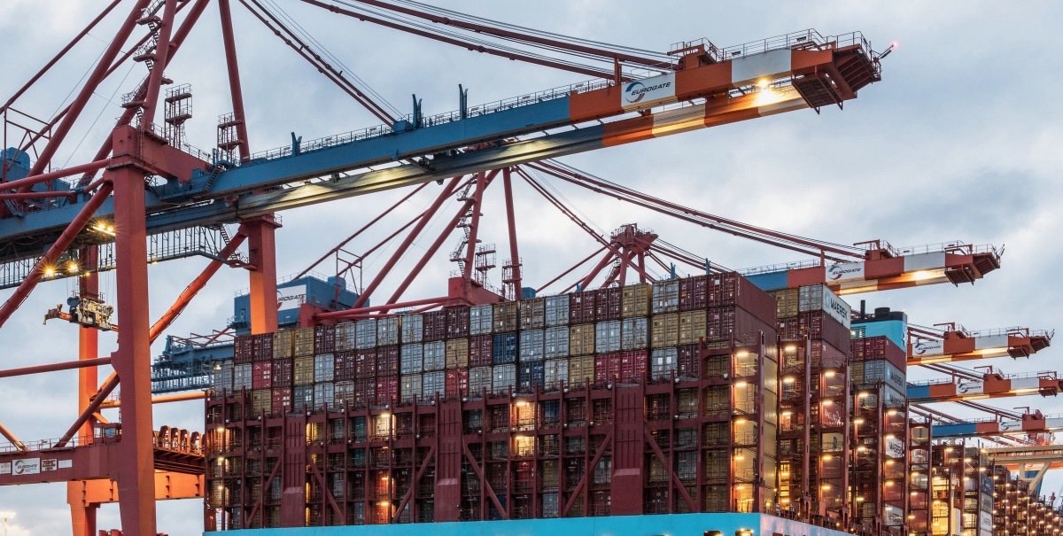 Container ship being loaded at a port under gantry cranes at dusk