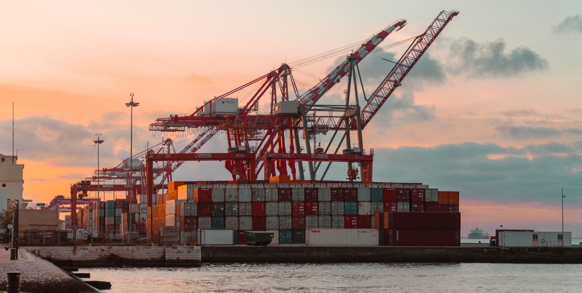 Container cranes and stacked containers at a port at sunset